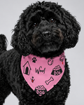 Black dog wearing a pink bandana with dog-themed designs on a gray background