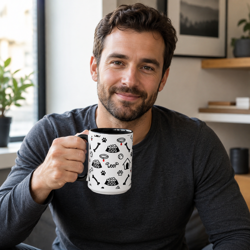 Man holding a mug with a black and white design, sitting indoors.