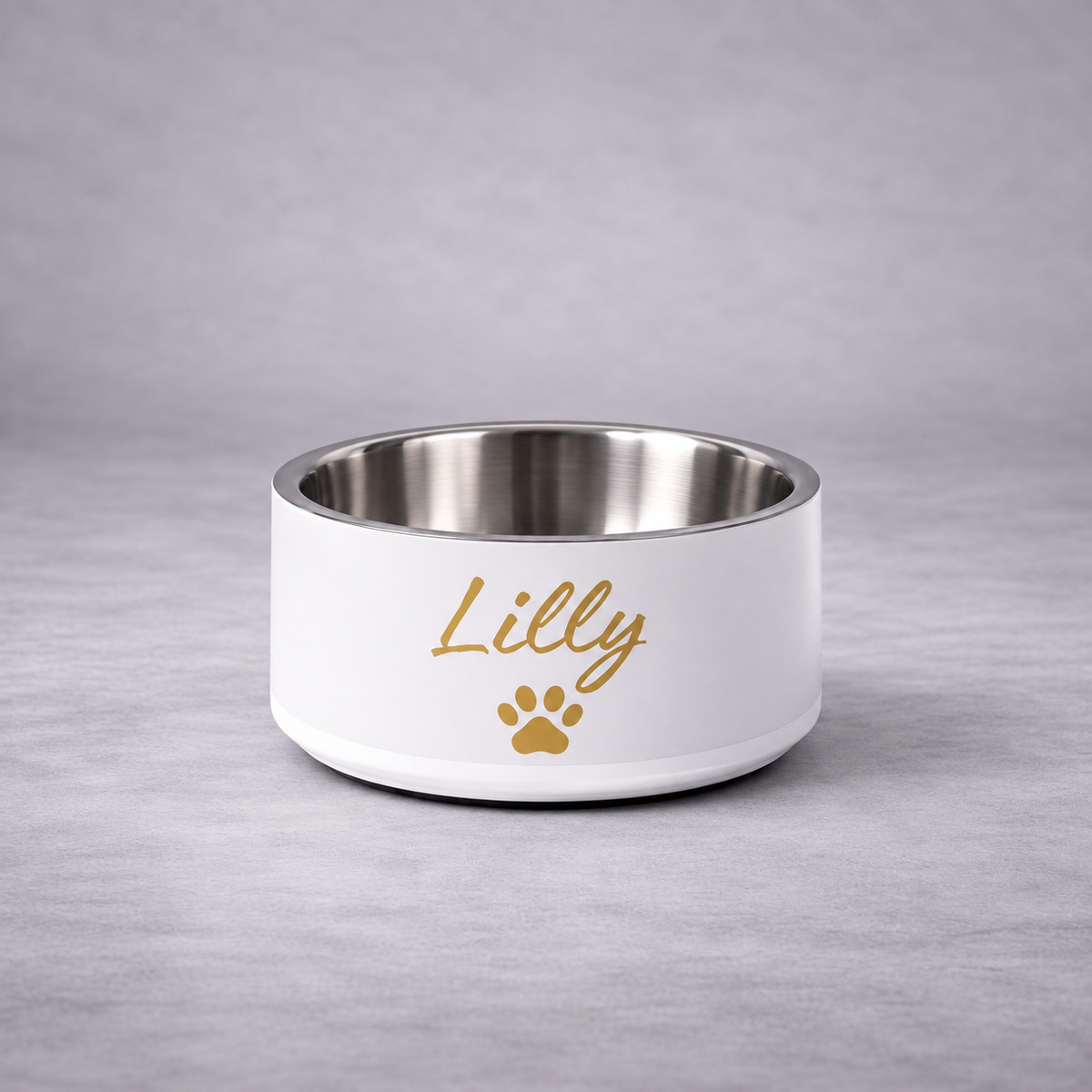 A ivory pet bowl with a stainless steel interior, with the name 'Lilly' in gold script and a gold paw print, set against a neutral gray background.