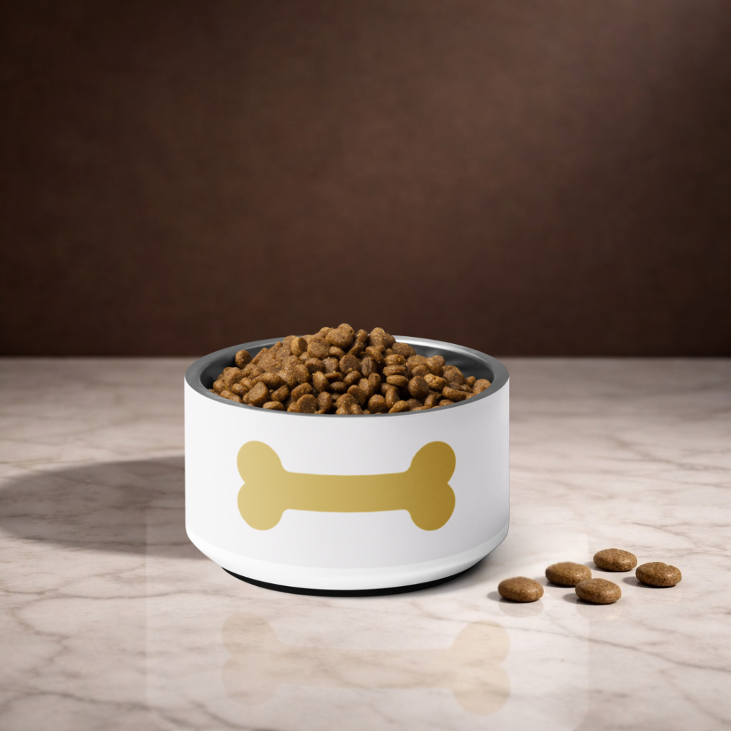 Ivory dog bowl with a gold bone design filled with dog food on a marble surface.