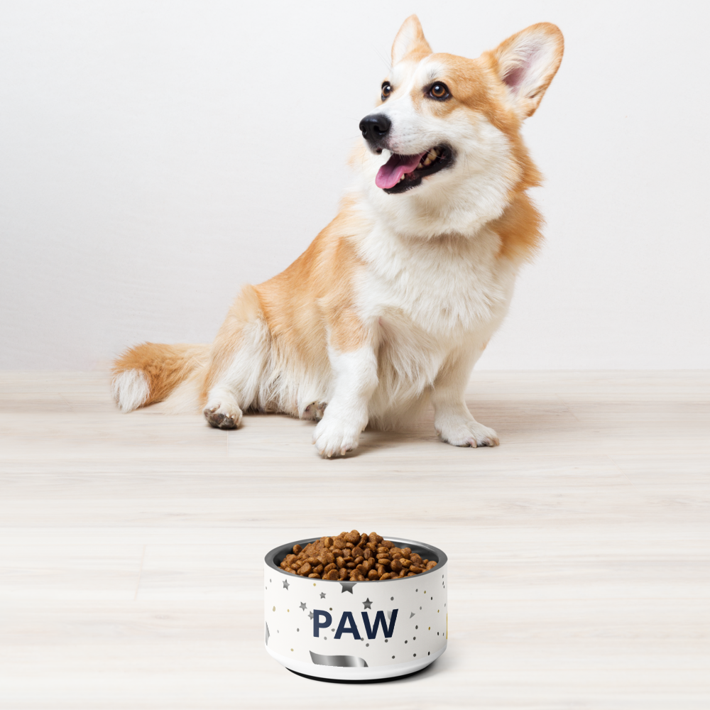 Dog sitting next to a bowl of food with 'PAW' on it against a white background