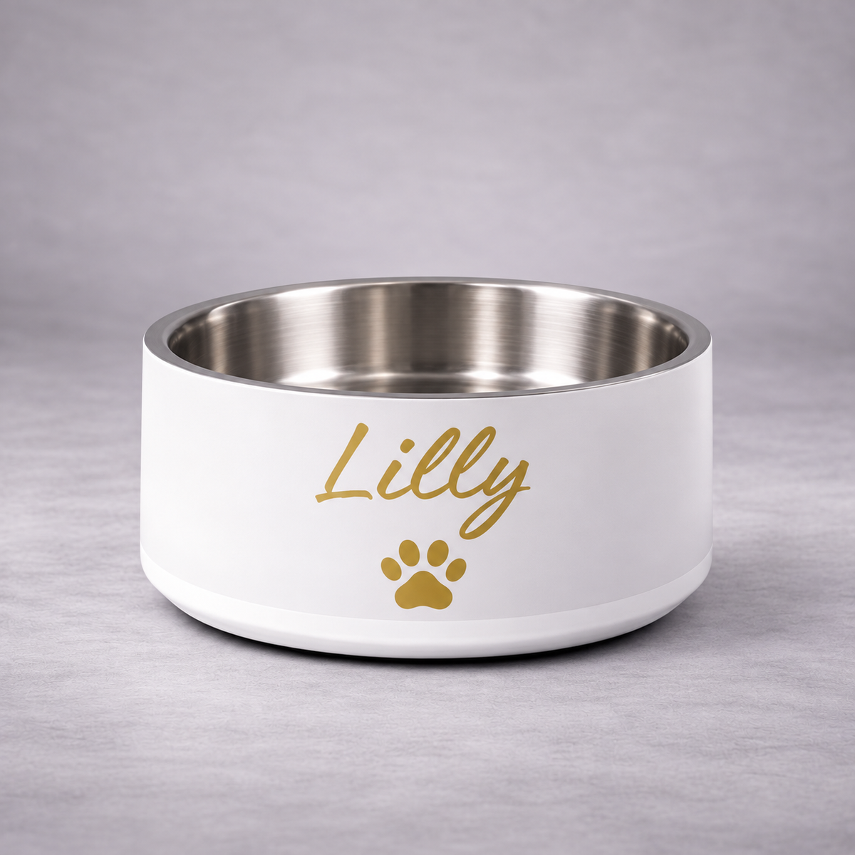 A ivory stainless steel pet bowl with the name 'Lilly' and a gold paw print on the front, set against a neutral gray background