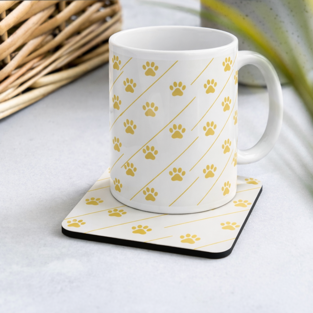 Ivory Whisper mug with gold  paw print pattern on a matching coaster on a light surface.