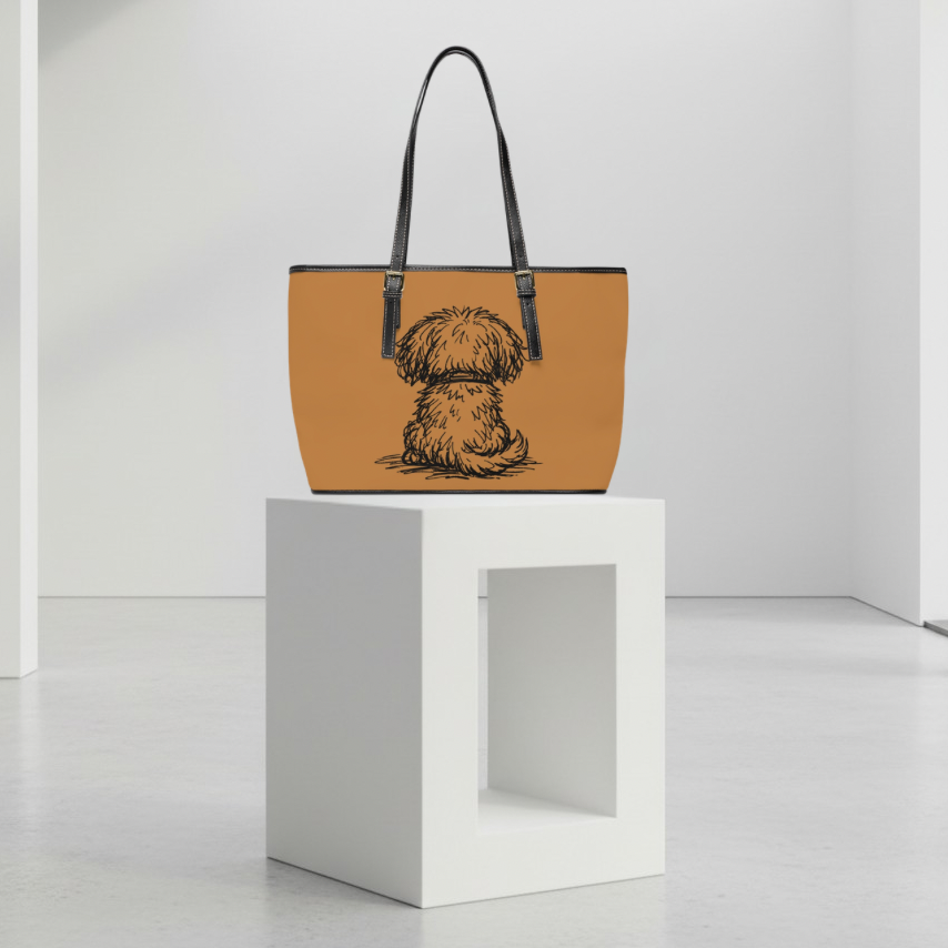 Tan handbag with a dog illustration on a white pedestal against a white background