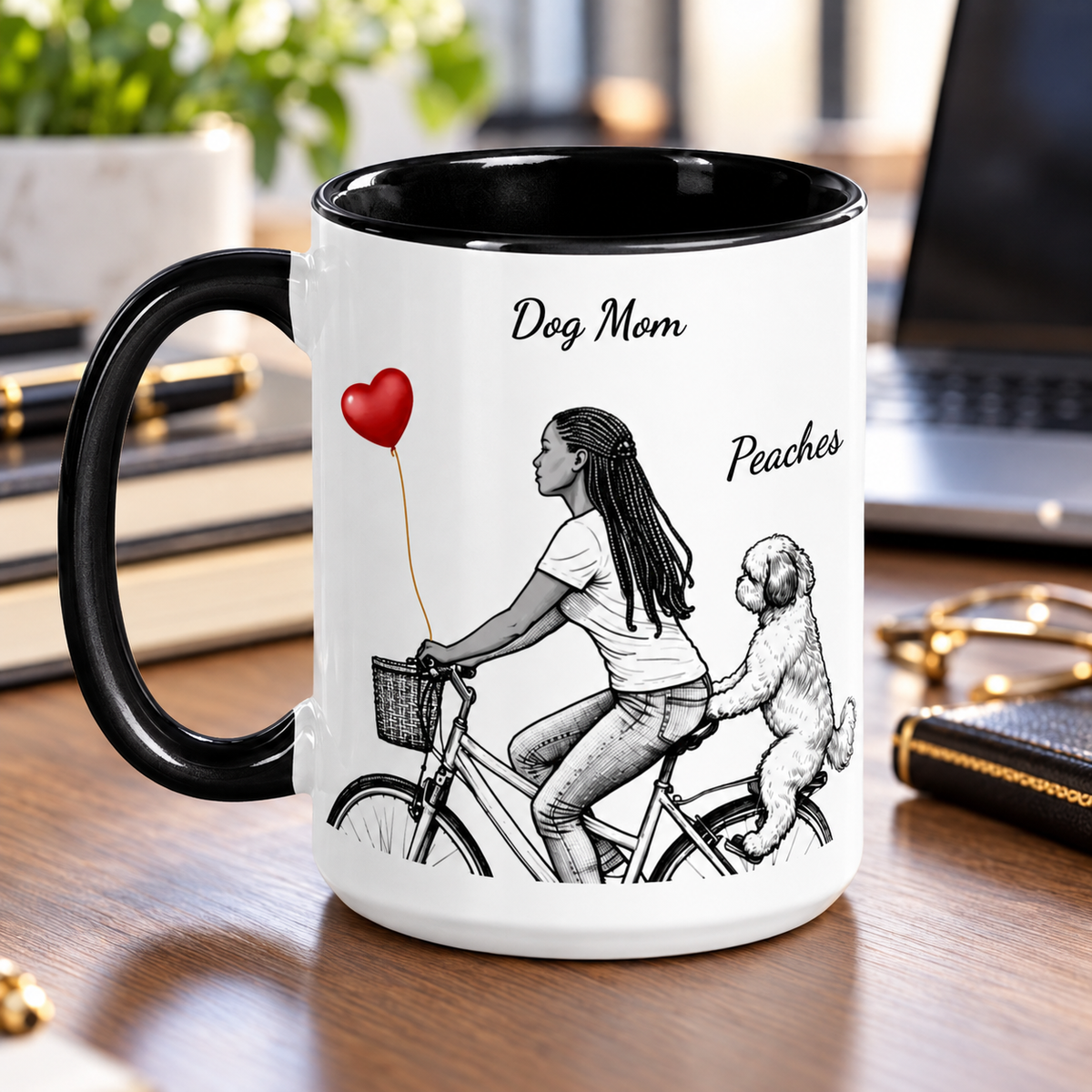 A white ceramic mug with a black handle and black interior, printed illustration of a black woman riding a bicycle with a dog and a red heart-shaped balloon. 