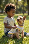 Toddler wearing the unisex "Spoiled Rotten" shirt with a dog wearing the "Spoiled Rotten" Sweater matching set sitting outside in the bark, by Uncommon Canine Couture Co