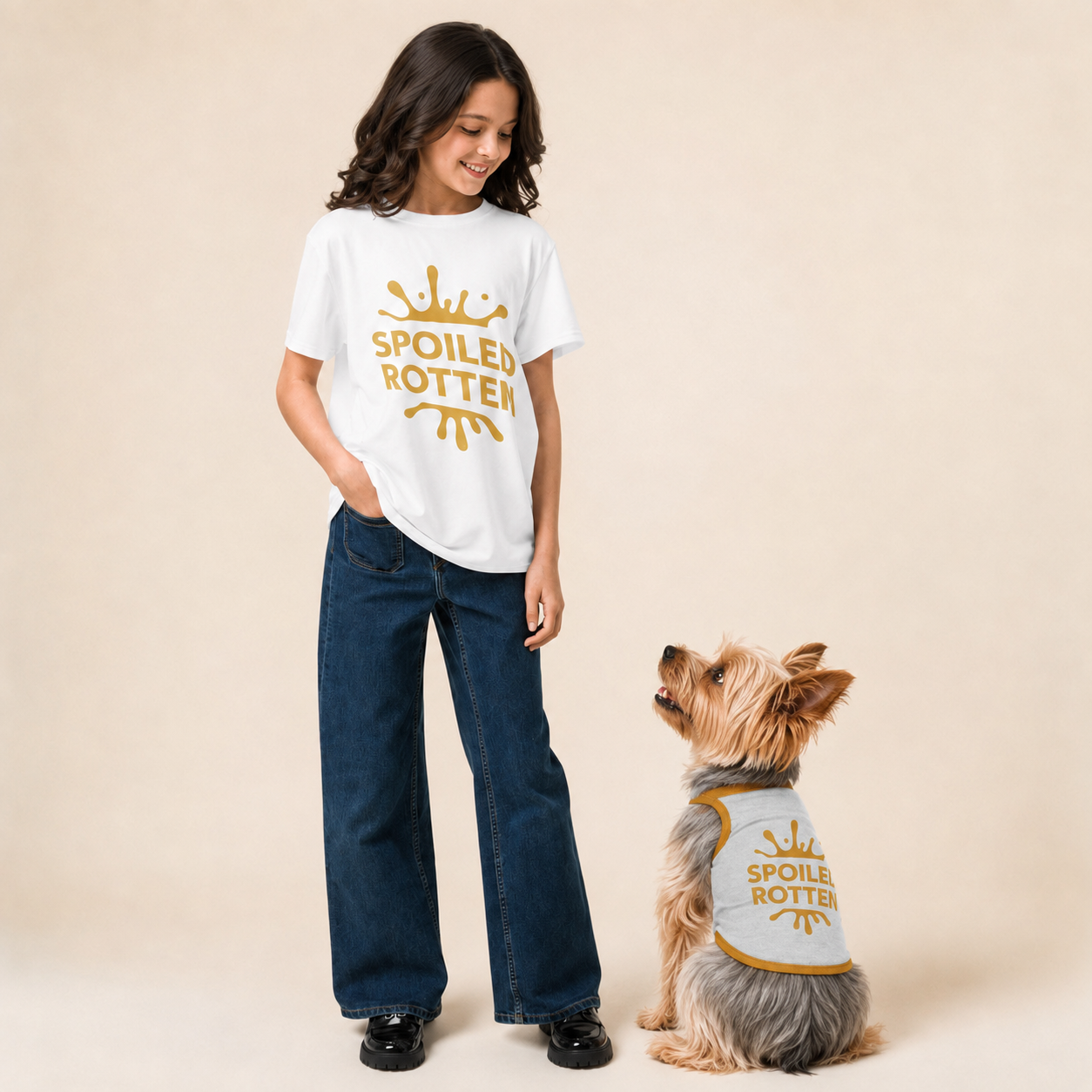 Young girl stands next to a small dog, both wearing matching white t-shirts and sweater with a gold splash graphic and the words 'SPOILED ROTTER'. 