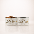 Two stylish personalized ivory stainless steel dog bowls with various patterns on a clean white background. 