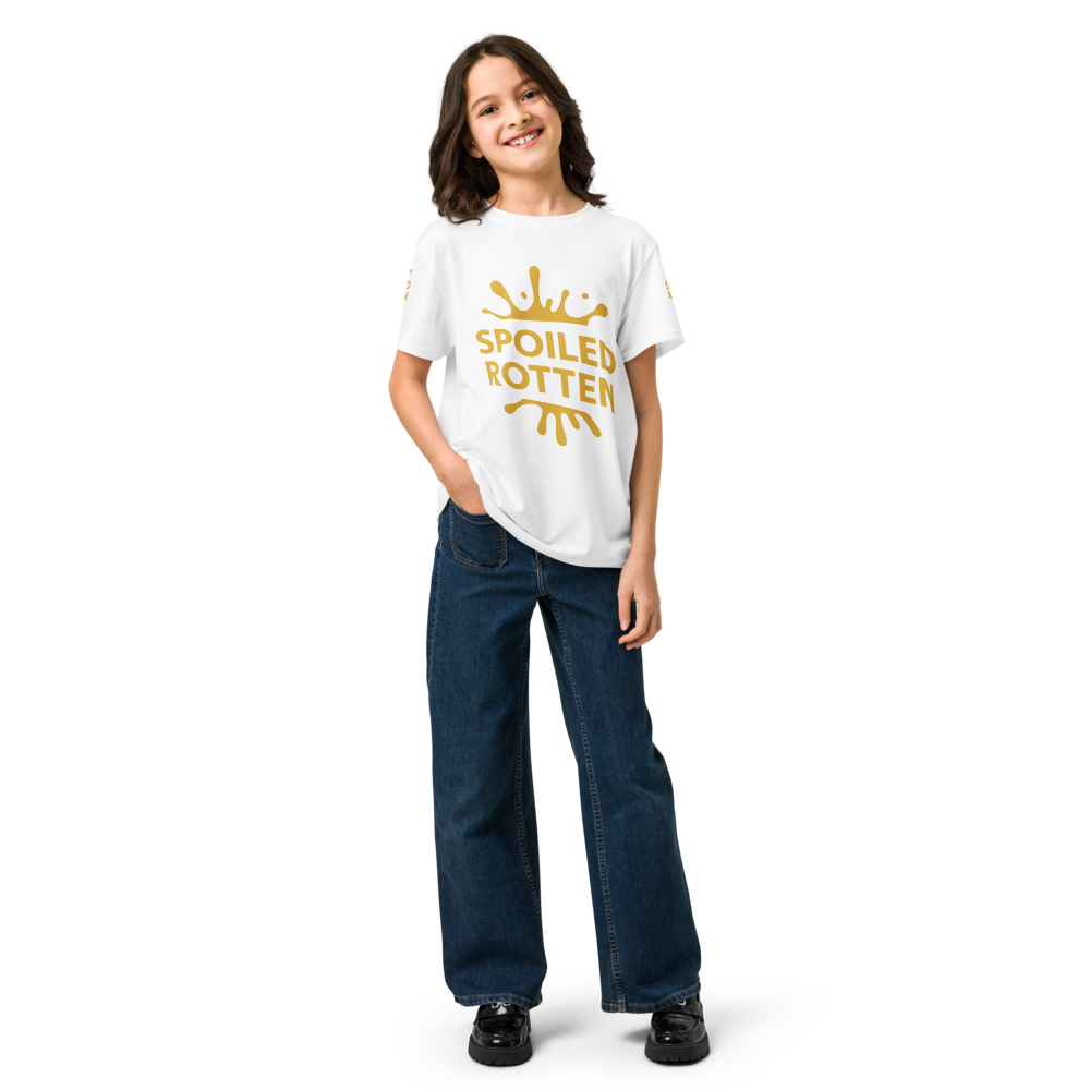 A young girl standing against a white background, wearing a white crewneck t-shirt with a gold splash graphic and the words 'SPOILED ROTTEN' printed on the front.
