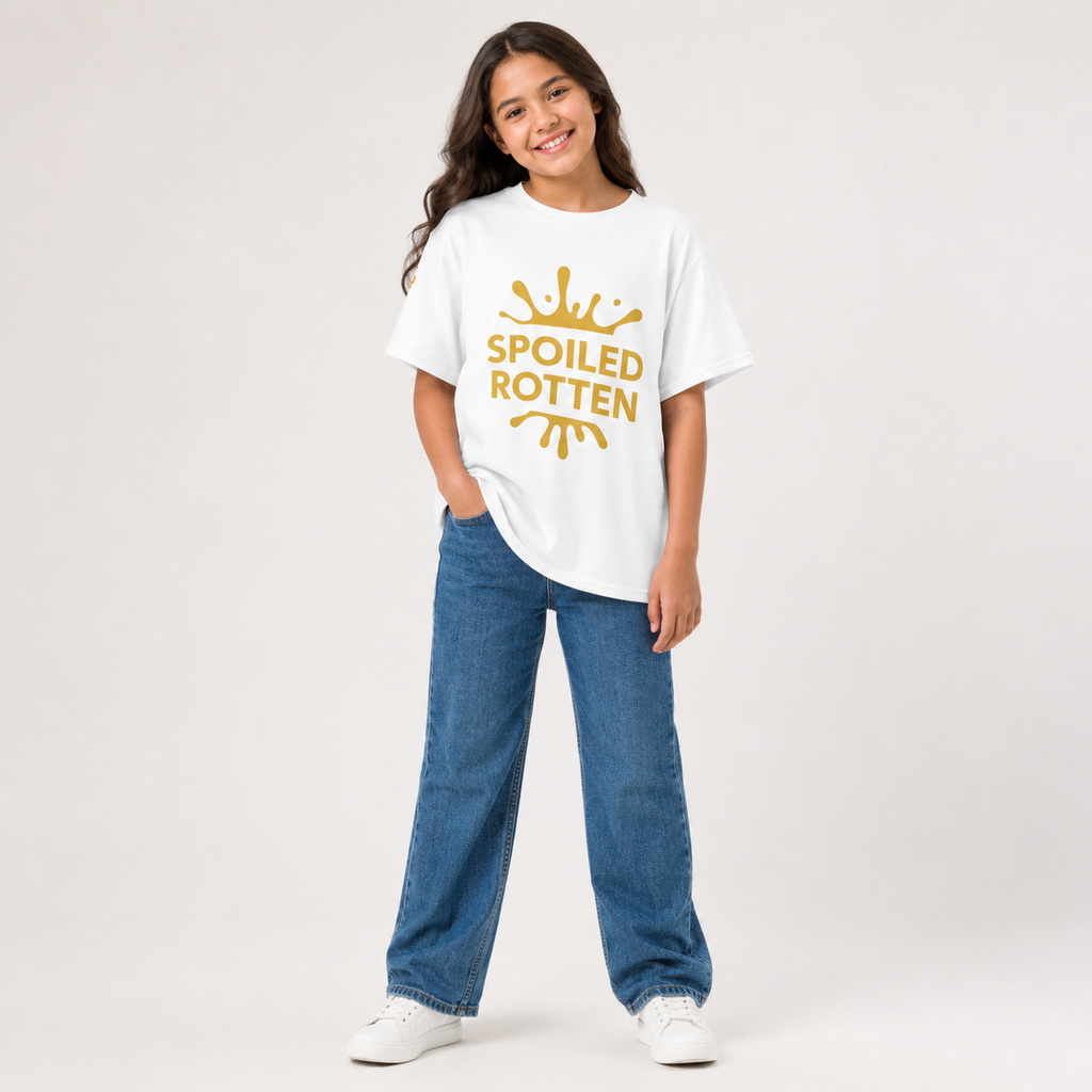 A young girl modeling a white t-shirt with a gold splash and 'SPOILED ROTTEN' graphic, paired with blue jeans and white sneakers. 