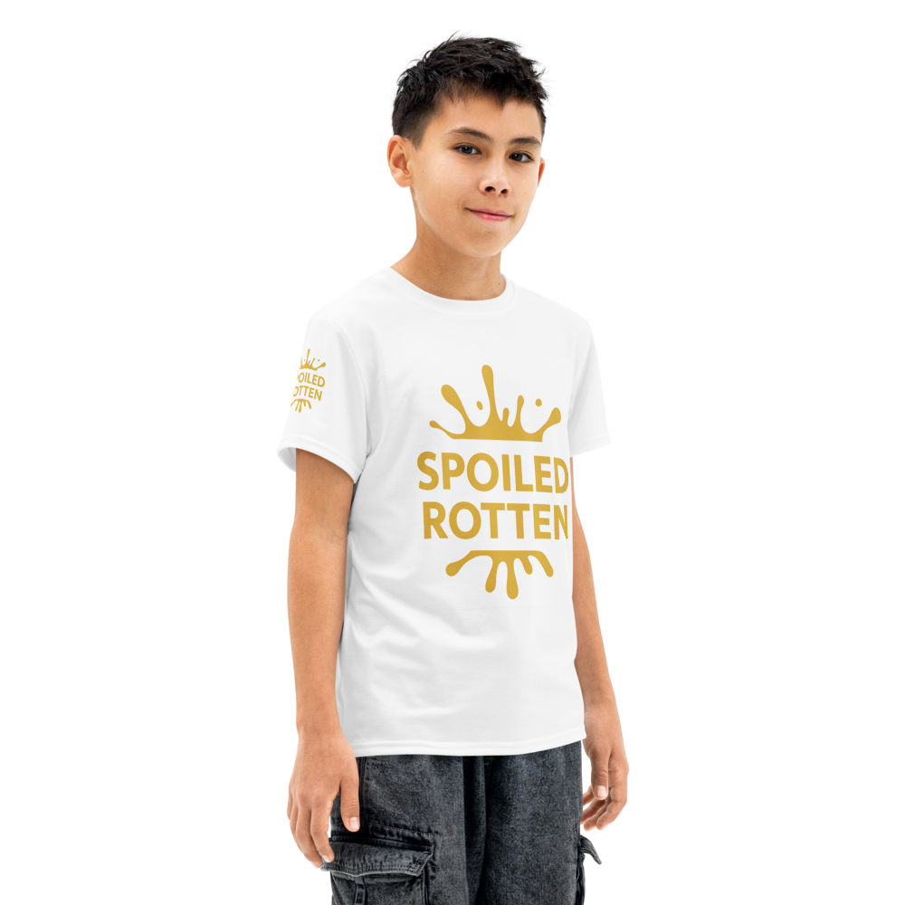 A young boy modeling a preppy white short-sleeve t-shirt with a gold splash graphic and the words 'SPOILED ROTTEN' all over print.