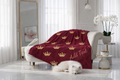 Burgundy blanket with gold crowns and 'Add Text' on a white sofa in a bright room.