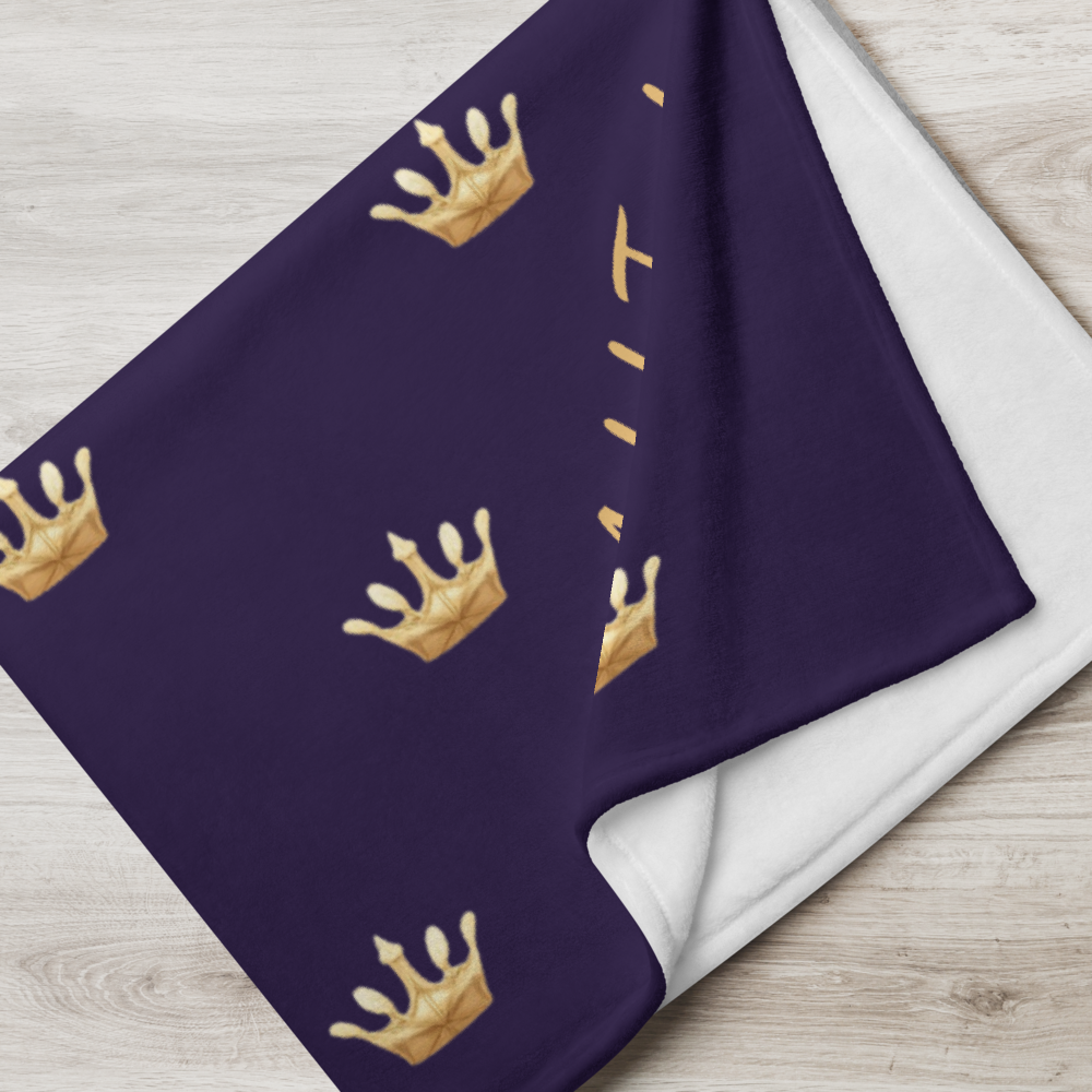 Purple blanket with gold crowns on a wooden surface