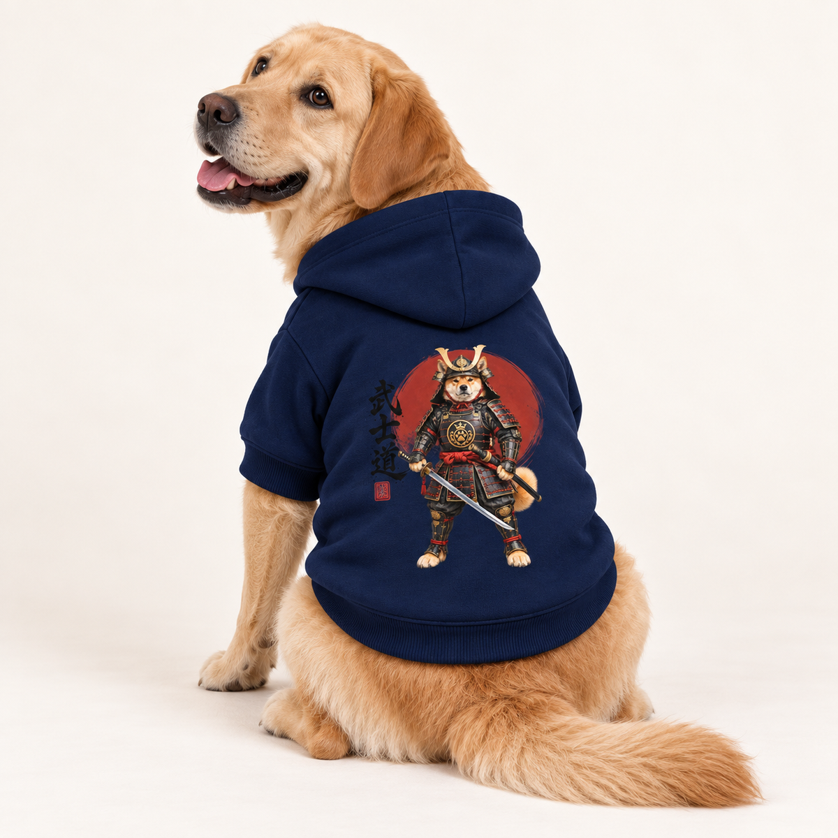 A medium size Labradorwearing a navy blue pet hoodie with a graphic of a samurai dog against a red sun, on a clean white studio background.