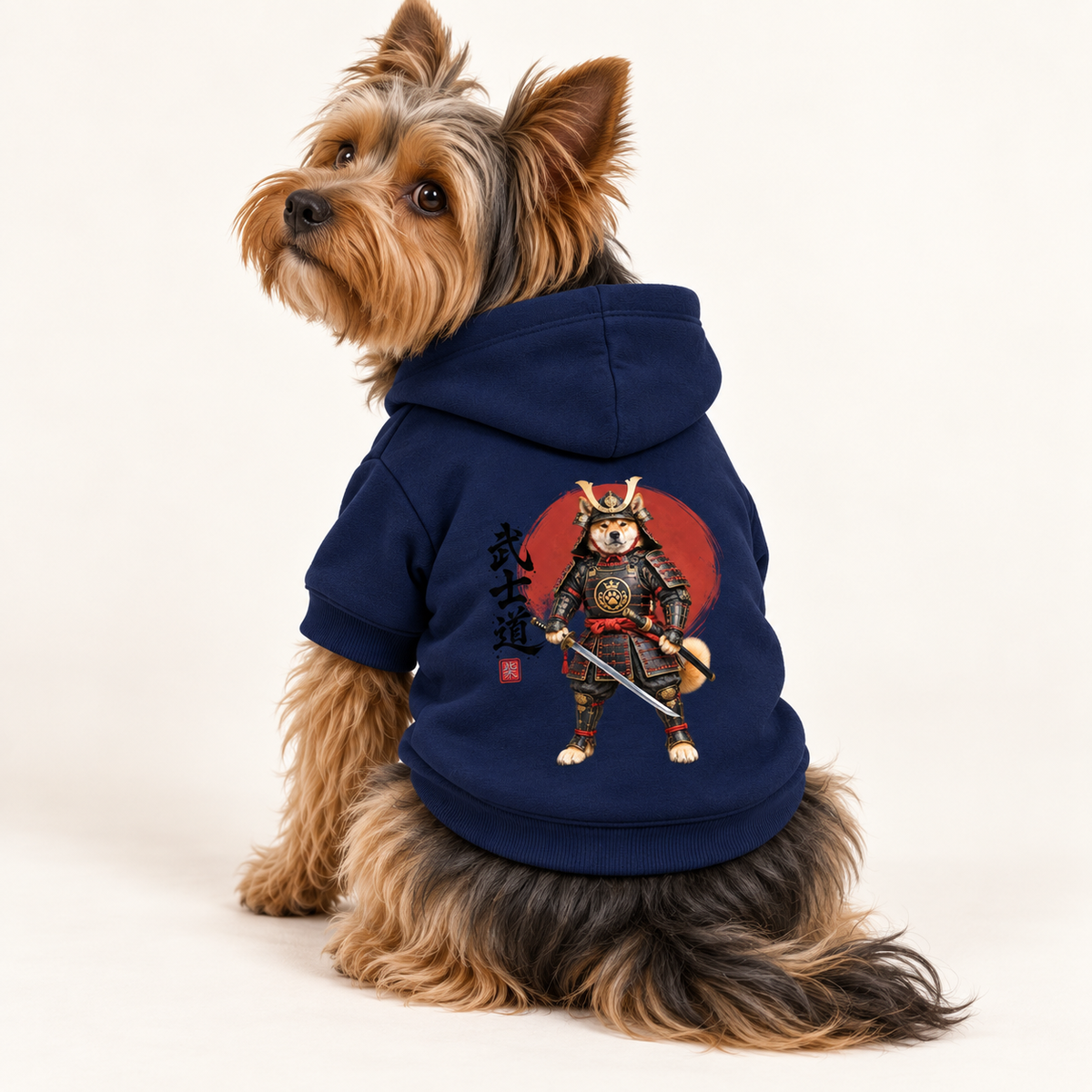 A Yorkshire Terrier wearing a navy blue dog hoodie with a samurai dog graphic on the back, photographed against a white background.