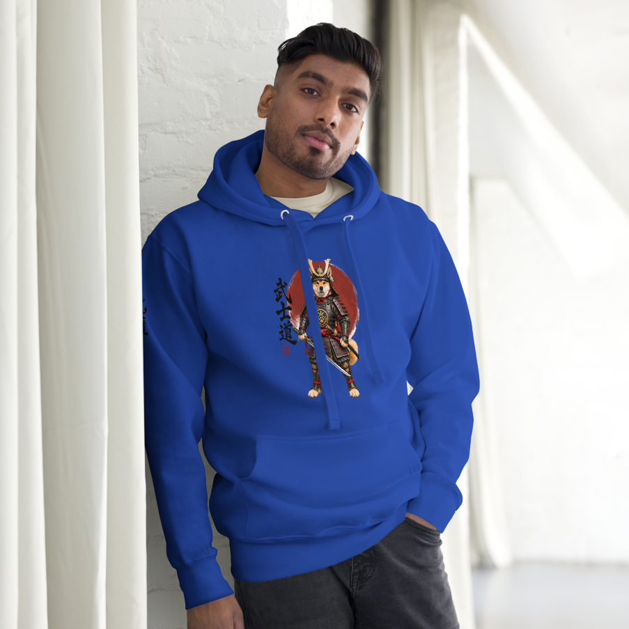 A man wearing a royal blue hoodie with a samurai graphic print, standing in a bright, modern room with white walls and curtains.