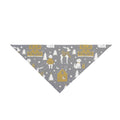 A dog bandana with a winter village pattern featuring golden houses, white dogs, reindeer, and pine trees.